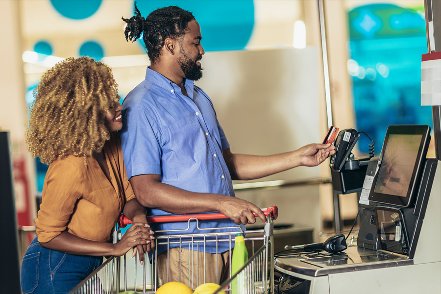 Pareja con tarjeta bancaria comprando alimentos en la caja de la tienda o supermercado